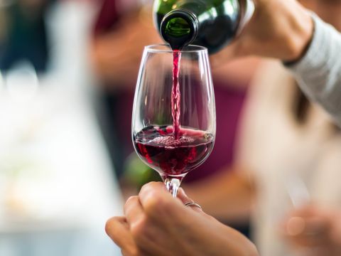 Kärbitud käed valavad punast veini veiniklaasis